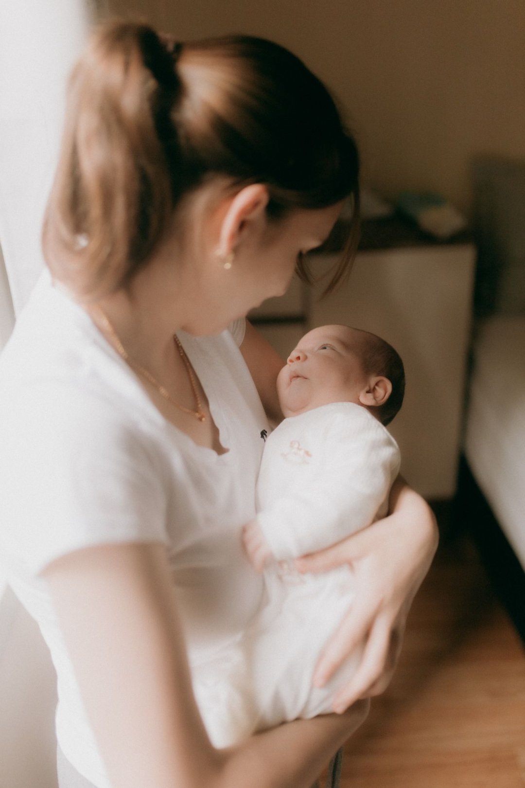 柔らかな光の中で眠る新生児を抱く母親